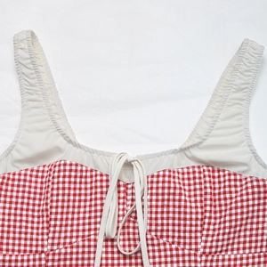 Close-up of red and white gingham pattern with thin shoulder straps and drawstring detail
