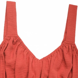 Detailed close-up of rust red textured V-neck sleeveless dress with pleated neckline