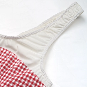 Macro detail showing high-quality stitching on red gingham fabric with elastic band
