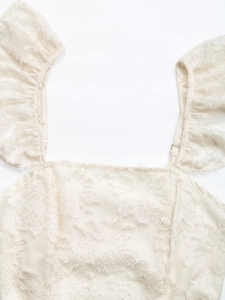 Detail of cream ruffle top with textured floral fringe fabric and elegant square neckline