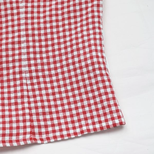 Close-up of red and white gingham fabric showing flat seam and hem stitching detail