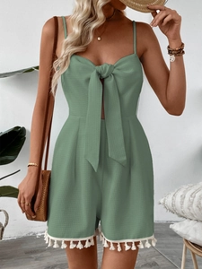 Close-up of sage green waffle fabric romper with delicate white tassel trim and tie-knot bow