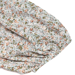 Detail of floral puff sleeve cuff with elastic smocking on light blue summer jumpsuit