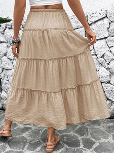 Detail of khaki layered maxi skirt featuring an elastic waist and flowing tiered design