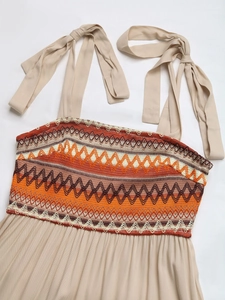 Detail of bohemian embroidery and pleated fabric on beige strap dress bodice