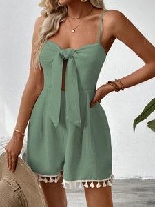 Detail of sage green waffle fabric romper featuring tassel hem and bow tie neckline
