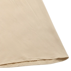 Détail de l'ourlet de la robe beige avec des coutures fines et un tissu lisse de qualité