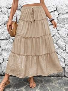 Detail of khaki tiered maxi skirt showing elastic drawstring waist and beaded accents