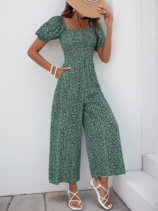Detail of smocked square neck bodice and floral print on dark green wide-leg jumpsuit