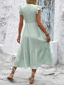 Back view of mint green smocked dress with ruffled sleeves and textured tiered skirt