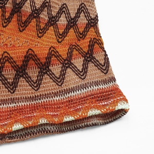 Macro view of knitted wavy pattern fabric in orange and brown with fine edge stitching