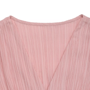 Détail d'une robe rose à col en V montrant la texture gaufrée du tissu seersucker