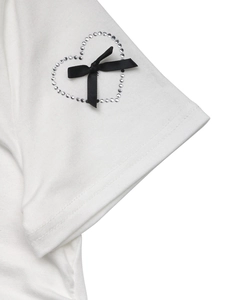 Detailed macro view of white cotton sleeve with silver rhinestone heart and black satin bow