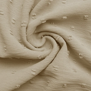 Detailed close-up of beige Swiss dot fabric texture showing delicate 3D polka dot patterns