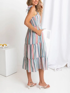 Detail of colorful striped summer dress featuring smocked bodice and tie straps