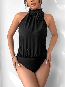 Détail d'un body noir dos nu avec fleur 3D et décorations de perles élégantes