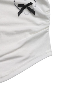 Detail of a white fitted T-shirt with a black ribbon bow and sparkling rhinestone heart