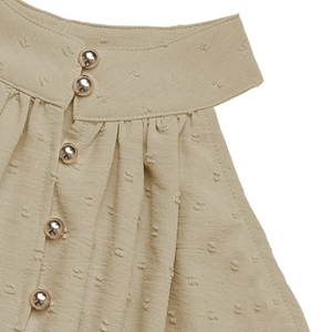 Detail of sage green Swiss dot dress with halter neck and golden metal buttons