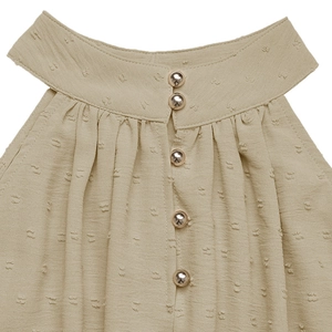 Close-up of khaki Swiss dot halter neck dress with metallic gold buttons and pleated collar