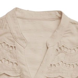 Detailed close-up of V-neckline with delicate wave embroidery on beige texture blouse
