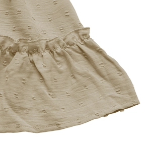 Detail of khaki Swiss dot fabric featuring ruffled edges and delicate textured patterns