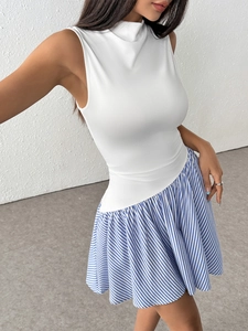 Dettaglio del top bianco senza maniche a dolcevita con gonna asimmetrica a righe blu
