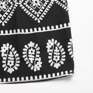 Détail des motifs cachemire et floraux sur le tissu noir d'une robe d'été ethnique
