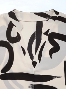Detail view of V-neckline and abstract geometric print on light woven fabric top