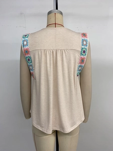 Detail of colorful crochet trim on the armhole of a beige sleeveless knit top for women