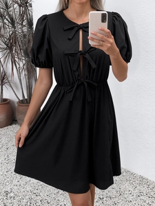 Détail de la robe noire à manches bouffantes avec nœuds décoratifs et découpe élégante