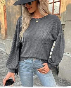 Detail of dark gray waffle knit texture with functional chest pocket and lantern sleeves