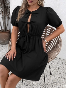 Détail des manches bouffantes et des nœuds sur une robe courte noire élégante d'été