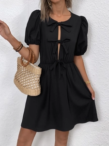 Détail d'une robe noire à manches bouffantes avec nœuds et découpes verticales