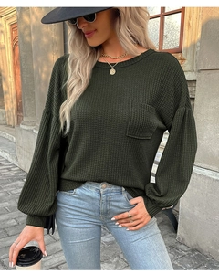 Close-up of deep green waffle knit texture and pocket detail on woman long sleeve top