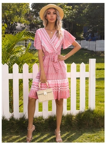 Detail of pink summer dress with white geometric print, V-neck, ruffle sleeves and tie-waist