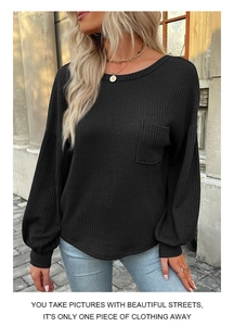 Detail of waffle knit fabric texture on black long sleeve top with chest pocket