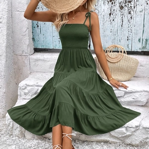 Dark green tiered A-line sun dress with smocked waist and spaghetti straps in outdoor setting