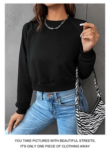 Detail of a black crew neck cropped sweatshirt with ribbed cuffs and soft cotton texture