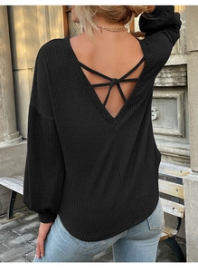 Detail view of black waffle knit top with open back cross strap design and loose fit sleeves
