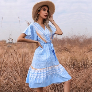 Summer V-neck floral blue dress with short sleeves and waist tie on a grassy field