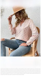 Detail of pink long-sleeve blouse with gold dots and white crochet lace V-neckline