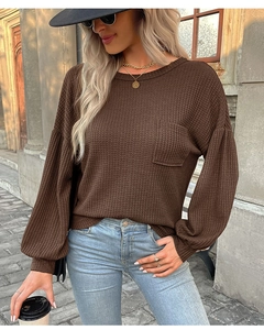 Detailed close-up of brown waffle knit fabric texture on casual long sleeve top with pocket