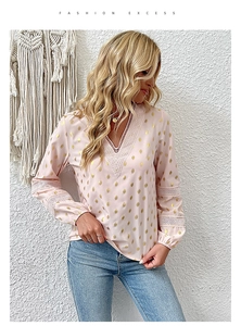Close-up of pink V-neck blouse with gold polka dots and white geometric lace details