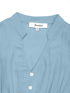 Détail de robe bleu clair à col en V montrant le tissu seersucker et boutons