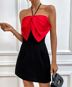 Detail showing high-contrast red satin bow on a black halter-neck evening party dress