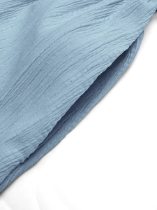 Détail de la texture plissée verticale et de la poche latérale d'une robe bleu clair