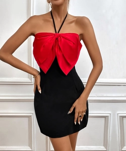 Detail view of bold red satin bow on a black contrast halter neck mini dress