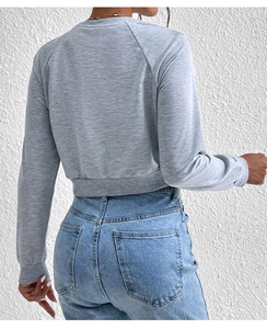 Back view of a cropped grey sweatshirt with raglan sleeves and ribbed cuffs on a model