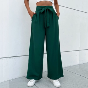 Detail of high-waisted dark green wide leg trousers with matching tie-waist bow and pleats