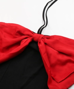 Detail of contrast red bow on black halter neck dress with smooth woven fabric texture